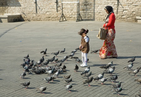 ISTANBUL - SEPTEMBER 10: mother and daughter feed doves on Taksim Square in major shopping,tourist and leisure district on September 10,2010 in Istanbul, Turkeyのeditorial素材