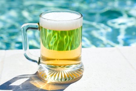 glass of cold beer on pool board in hot summer day の写真素材