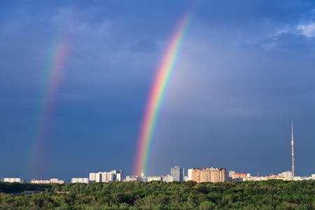 Double rainbow under city park in dark blue skyの写真素材