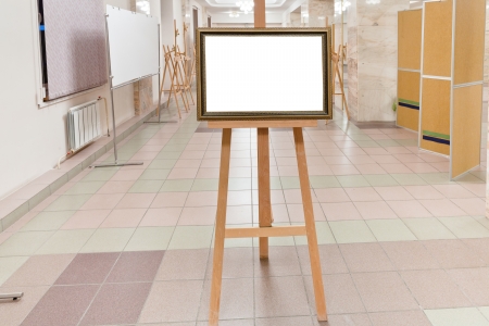 golden wood picture frame with white cut out canvas on easel in art gallery hallのeditorial素材