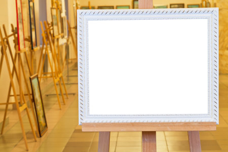 white picture frame with white cut out canvas on easel in gallery hall