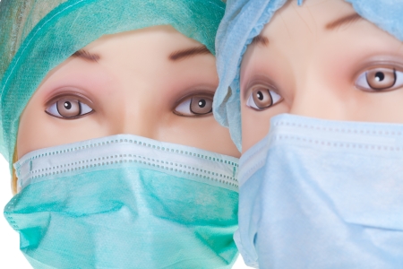 two female dummy doctor heads wearing textile surgical cap and medical protective mask close upの写真素材
