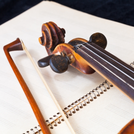 fiddle bow and scroll on music book close upの写真素材
