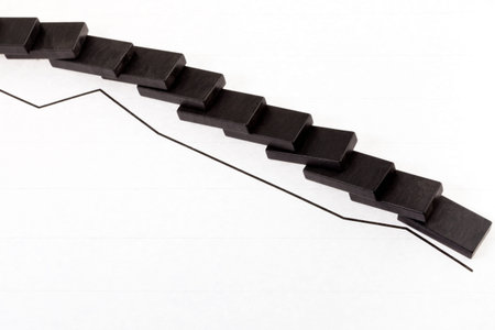 business concept - fallen domino and reducing economy graph