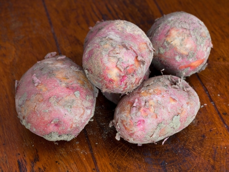 few pink raw potatoes on wooden tableの写真素材