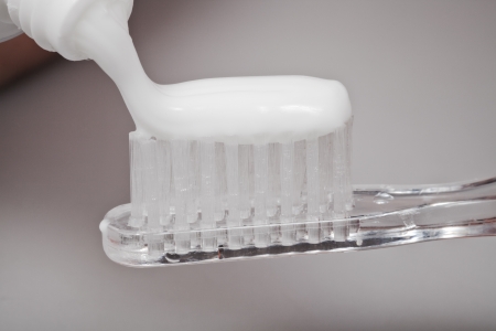 squeezing toothpaste from tube on toothbrush close upの写真素材