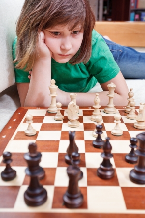 little girl playing chess game lying on couchの写真素材