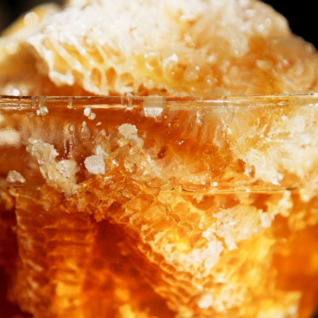 fresh honey in comb in glass dish at table close upの写真素材