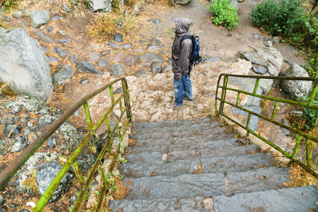 stone steps and tourist in rain in medieval geghard monastery in Armenia