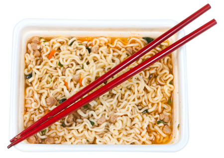 top view of cooked instant noodles and red chopsticks in foam cap isolated on white backgroundの写真素材