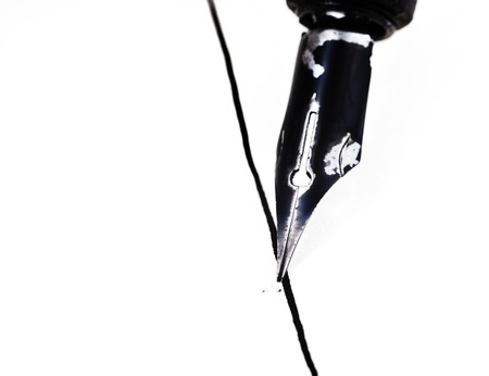 metal nib of drawing pen drafting straight line by black ink on white paperの写真素材