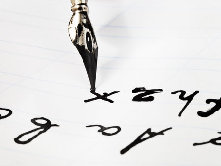 writing of set of letters by black ink nib on white sheet of notebook close up