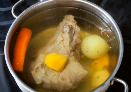 beef broth with seasoning vegetables in open pan on glass ceramic cookerの写真素材