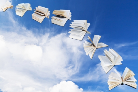 arch of flying books with blue sky and white cloud backgroundの写真素材