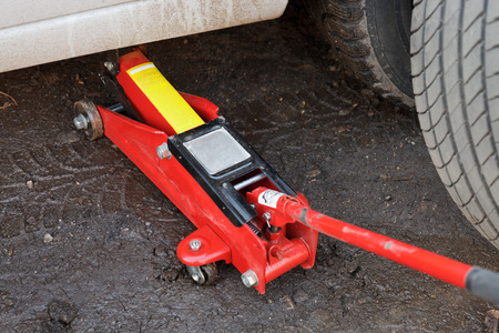 seasonal replacement of tires with jack outdoors - lifting car by jackの写真素材