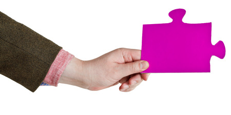 male hand holding big pink paper puzzle piece isolated on white の写真素材