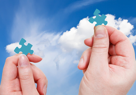 male and female hands with little puzzle pieces with blue sky with white clouds backgroundの写真素材