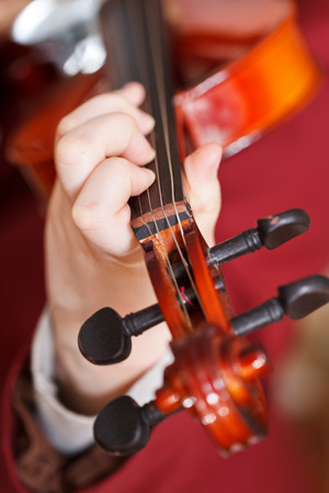 girl plays on fiddle - chord on fingerboard close upの写真素材