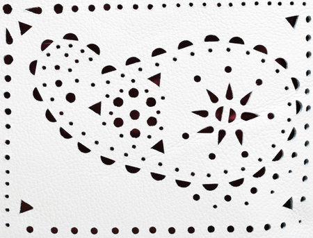 perforated paisley ornament on white leather close upの写真素材