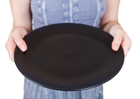 woman holds empty black plate isolated on white backgroundの写真素材