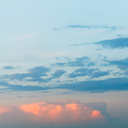 pink fluffy clouds in blue sunset sky in summer