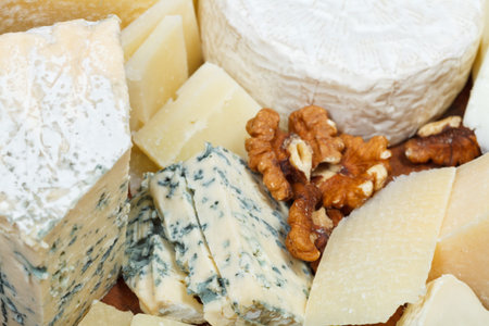 pieces of cheeses on wooden plate close up