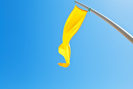 Beach safety yellow flag with blue sky backgroundの写真素材