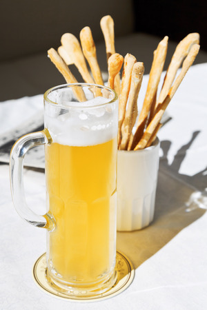 mug of beer and bread sticks on table at outdoor restaurantの写真素材