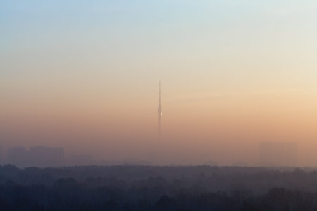 TV tower and fog over city at cold autumn dawn