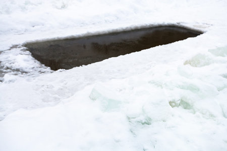 ice-hole with frozen water in pond and ice blocks in winter day