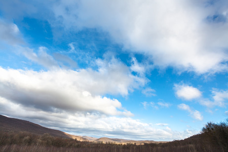 blue sky with white clouds over low Caucasus mountain in early spring dayの写真素材