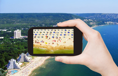 travel concept - tourist taking photo of Albena sand beach on mobile gadget, Bulgariaの写真素材