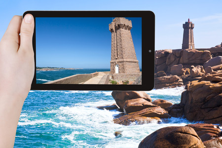 travel concept - tourist taking photo of Lighthouse on Pink Granite Coast in Brittany on mobile gadget, Franceの写真素材