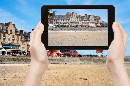 travel concept - tourist taking photo of waterfront in Cancale town on mobile gadget, Franceの写真素材