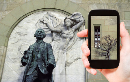 travel concept - tourist taking photo of walls and statue of Major Davel in Chateau Saint-Maire in Lausanne, Switzerland on mobile gadgetの写真素材