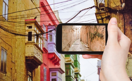 travel concept - tourist taking photo of medieval narrow street in Valletta on mobile gadget, Maltaの写真素材