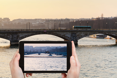 travel concept - tourist taking photo of bridges in Paris on yellow blue sunset on mobile gadgetの写真素材