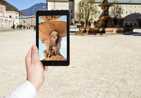 travel concept - tourist taking photo of fountain in Salzburg on mobile gadget, Austria
