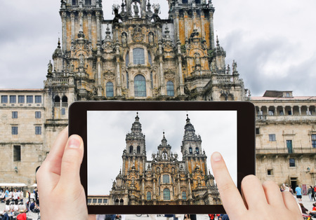 travel concept - tourist taking photo of The Cathedral of Santiago de Compostela on mobile gadget, Spainの写真素材