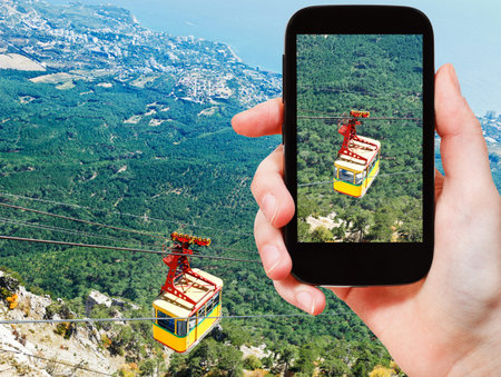 travel concept - tourist taking photo of Cableway Miskhor - Ai-Petri over Crimean mountains on...