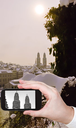 travel concept - tourist taking photo of Zurich city with towers of Grossmunster church in ewither evening on mobile gadget, Switzerlandの写真素材