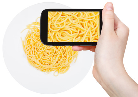 photographing food concept - tourist takes picture of italian spaghetti al burro on plate on smartphone, Italyの写真素材