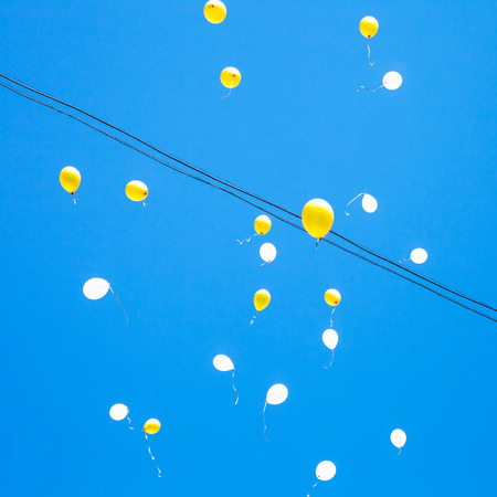 toy balloons float in blue sky in cityの写真素材