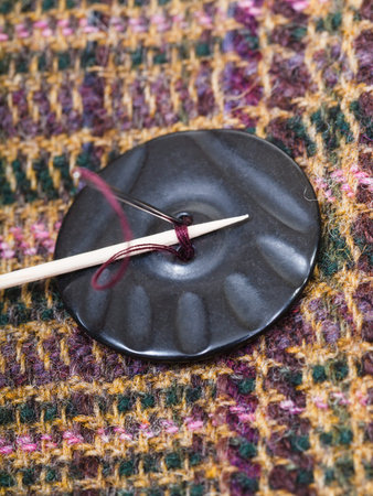 attaching of button to woolen fabric by needle close up
