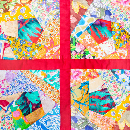 four details of hand made patchwork quilt framed in red cloth