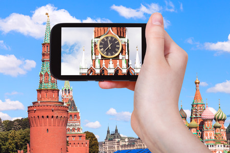 travel concept - tourist photographs picture of clock on Spasskaya tower of Moscow Kremlin on smartphoneの写真素材