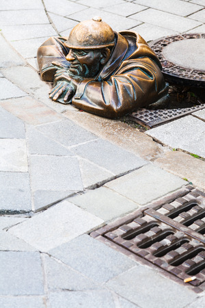 BRATISLAVA, SLOVAKIA - SEPTEMBER 23, 2015: Bronze sculpture of Cumil the Peeper - Man Under a Manhole Cover. The figure made by Slovak sculptor Viktor Hulik in 1997.のeditorial素材