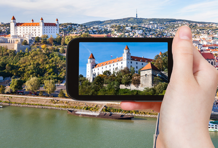 travel concept - tourist snapshot of Bratislava Hrad Castle over Danube River waterfront on smartphoneのeditorial素材