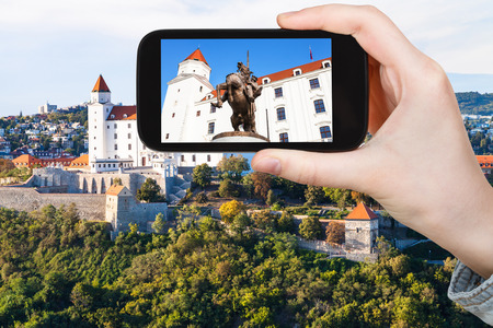 travel concept - tourist photos statue of King Svatopluk I in Bratislava Hrad castle on smartphoneのeditorial素材