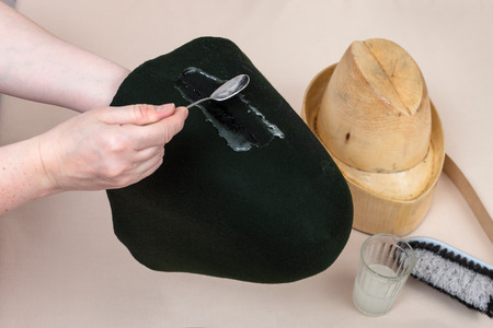 workshop for alpine felt hat making - hatter applies an adhesive a felt hood for shaping on wooden dummyの写真素材